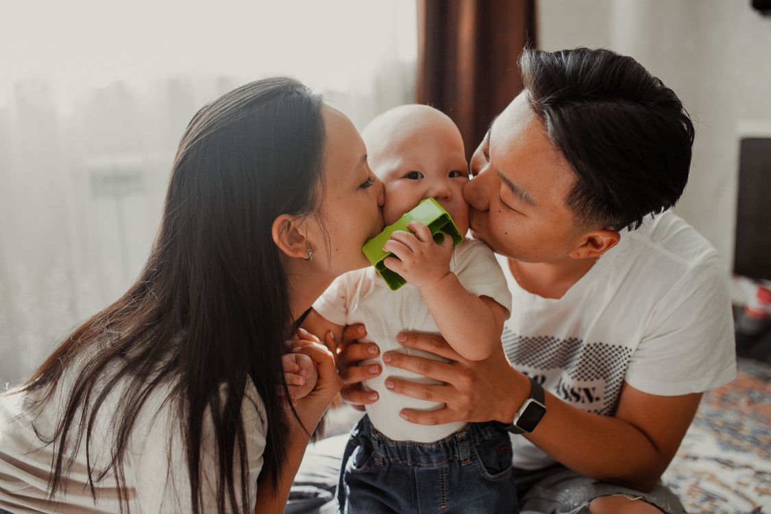Ouders kussen liefdevol hun baby, een intiem gezinsmoment