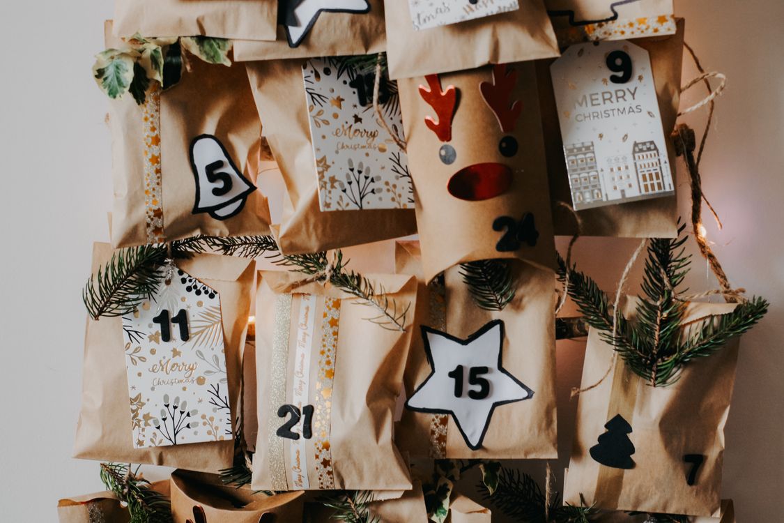Een zelfgemaakte adventskalender van genummerde papieren zakjes met dennengroen