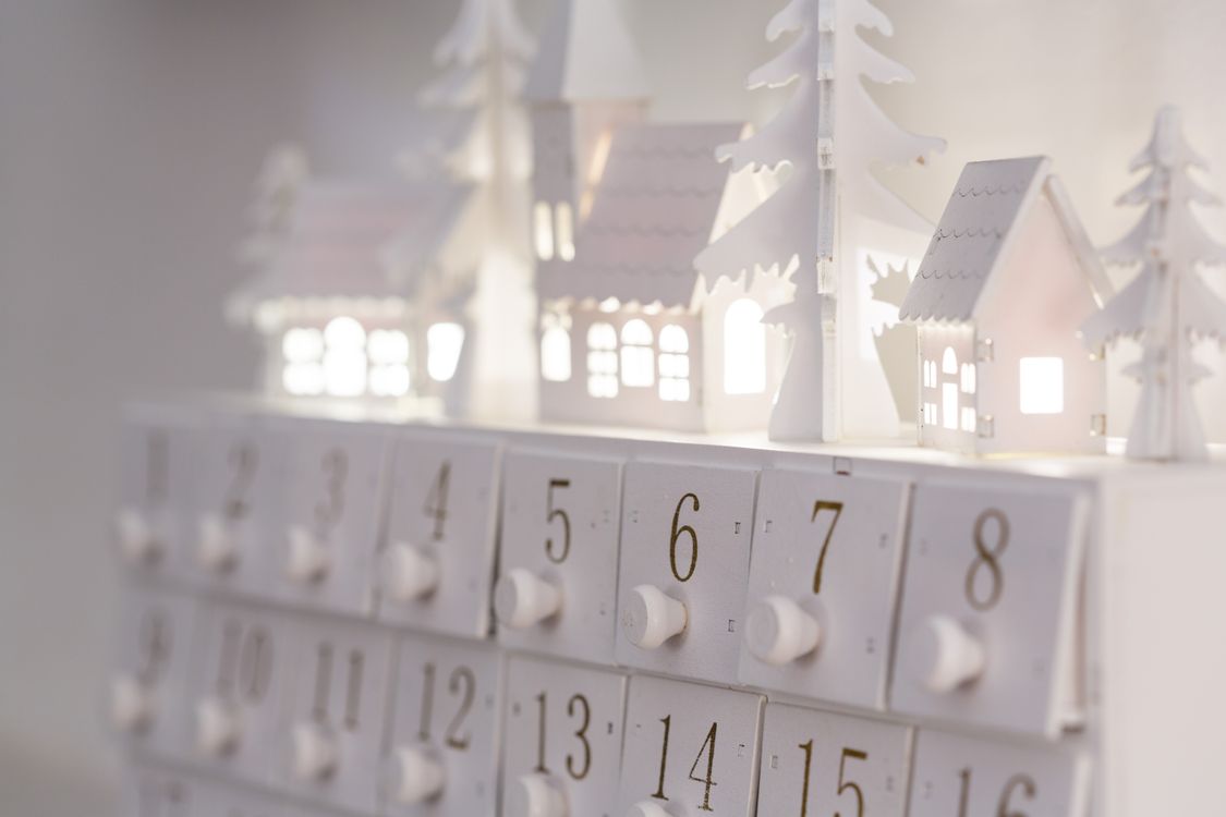 Een minimalistische adventskalender met verlichte huisjes en nummers