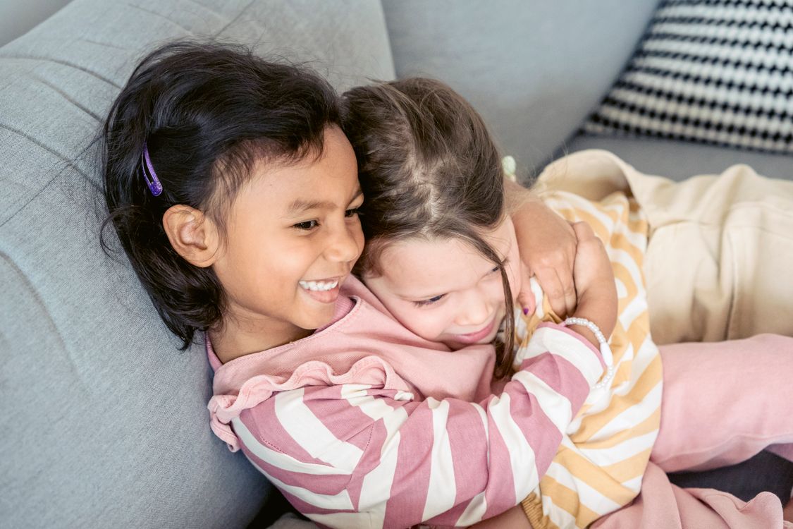 Drie vriendinnetjes zitten lachend naast elkaar buiten