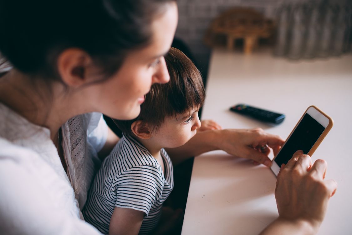 Ouder en kind kijken samen op een telefoon