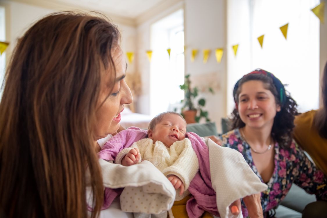 Moeder houdt haar pasgeboren baby vast, ingebakerd in een doek
