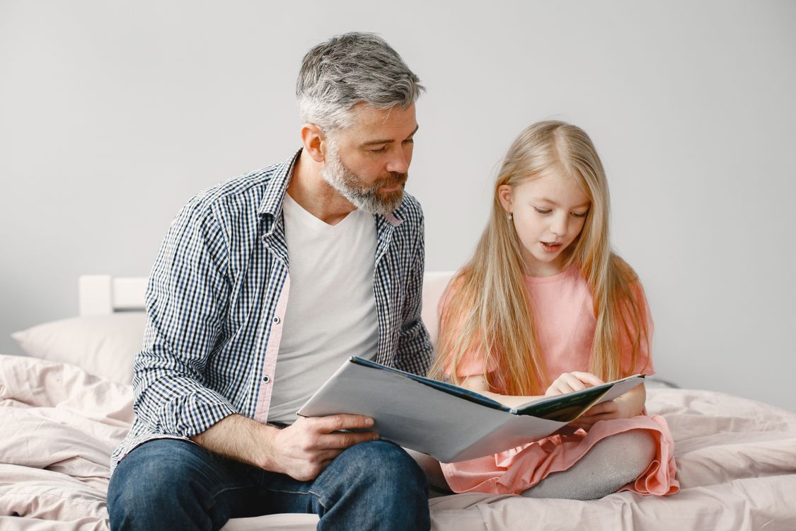 Vader leest zijn dochter een boekje voor voor het slapengaan
