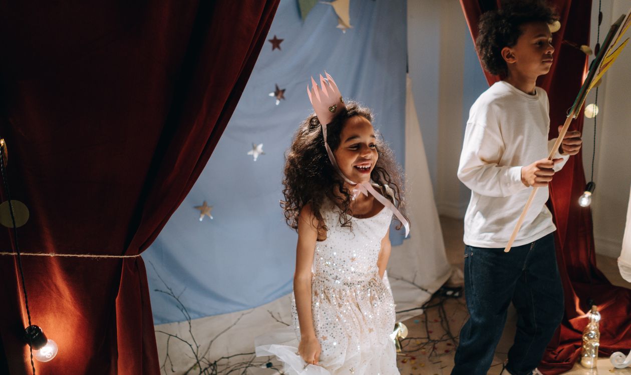 Twee kinderen in kostuum spelen een toneelstukje voor een gordijn