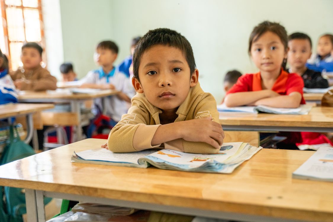 Kinderen in een klaslokaal steken enthousiast hun hand op
