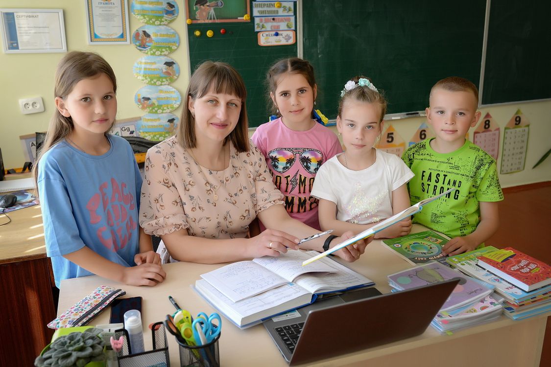 Kinderen in een klaslokaal luisteren aandachtig naar hun juf