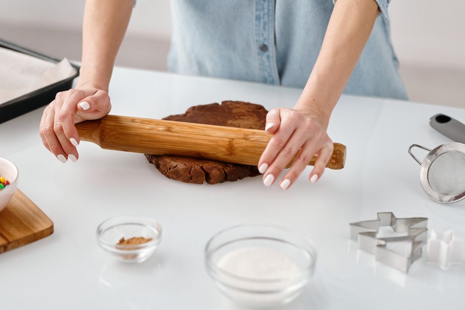Handen die deeg uitrollen op een werkblad