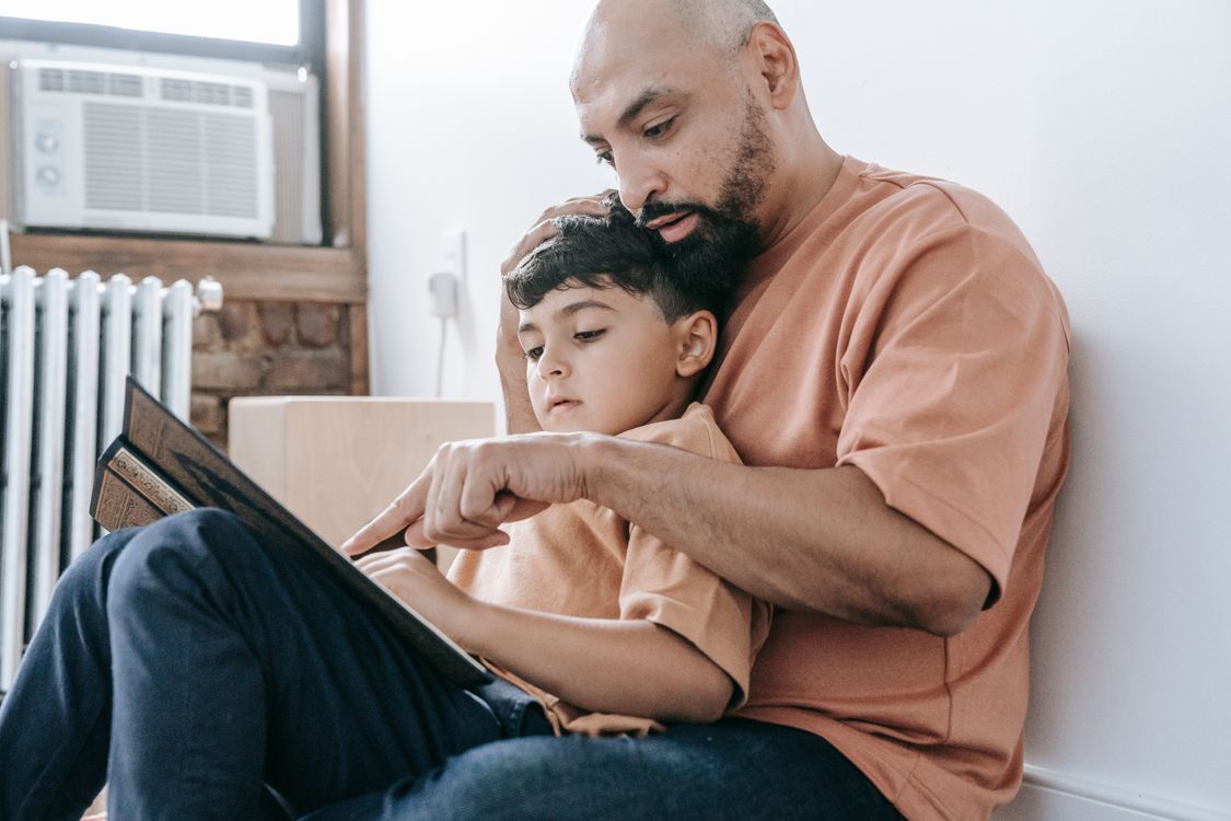 Een vader leest zijn zoon voor op de bank