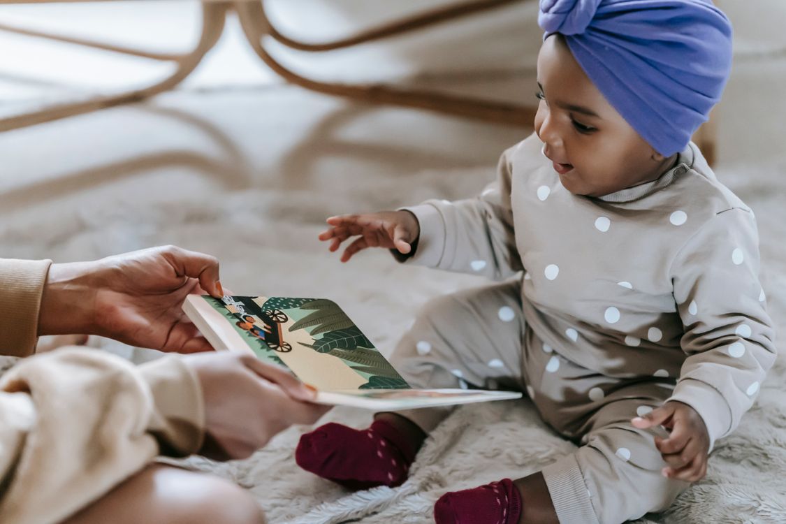 Ouder laat een kleurrijk prentenboek zien aan een peuter