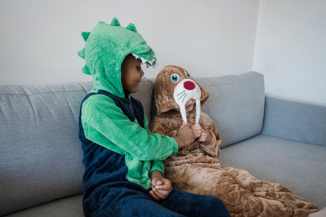 Twee kinderen in verkleedpakken spelen samen op de bank