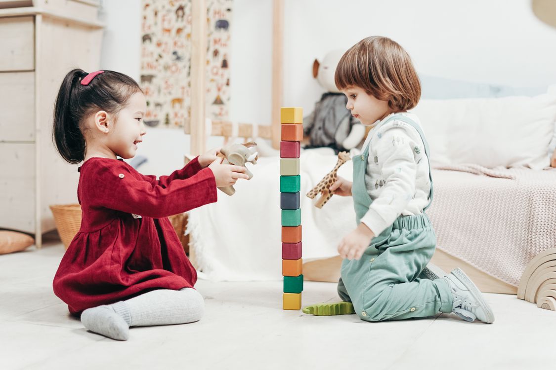 Twee kinderen bouwen samen met houten blokken op de grond