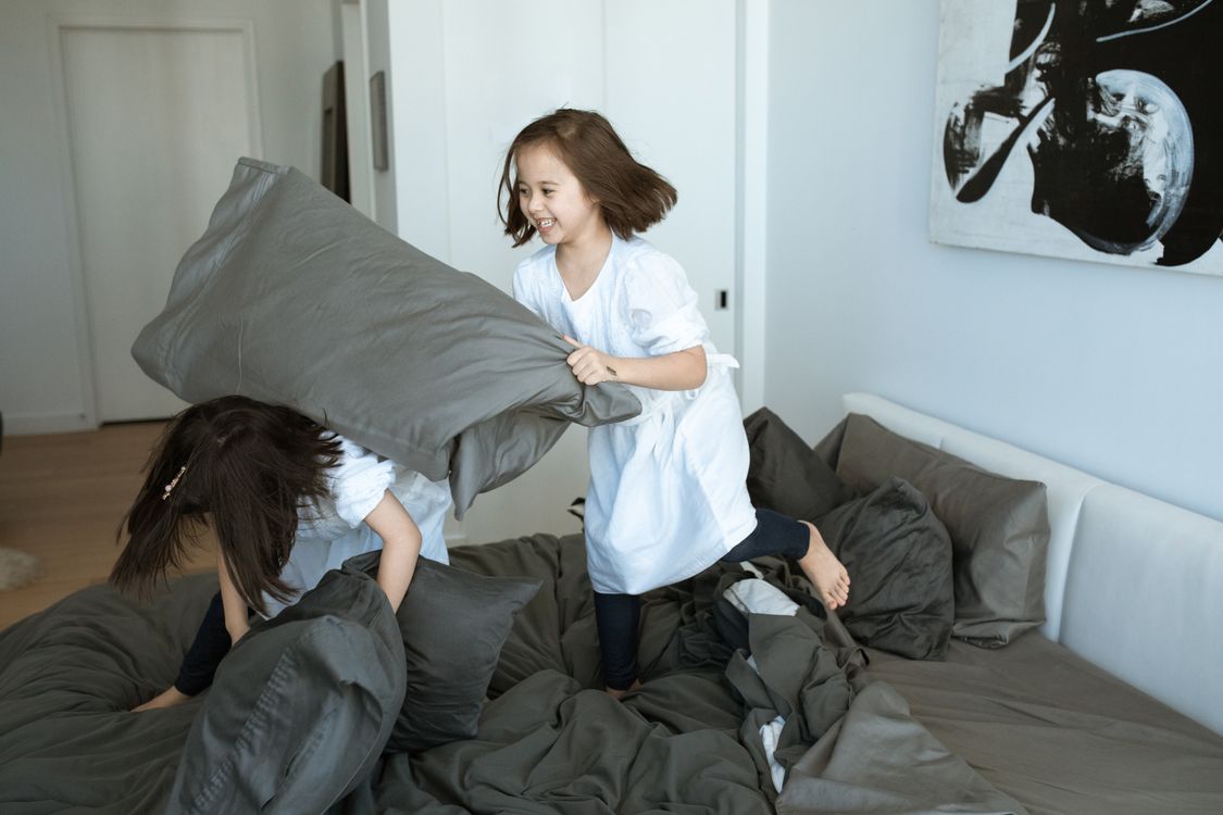 Twee kinderen stoeien lachend binnen op bed
