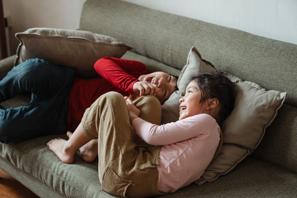 Twee kinderen die samen spelen en lachen op een bank