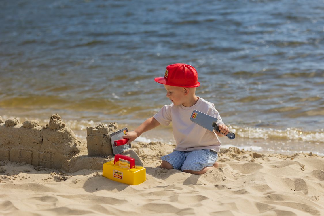 Jongetje bouwt een zandkasteel op het strand, een typische vakantieherinnering om later samen op terug te blikken