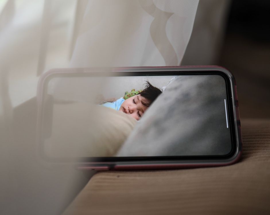 Smartphone-scherm toont een slapend kind via een babyfooncamera