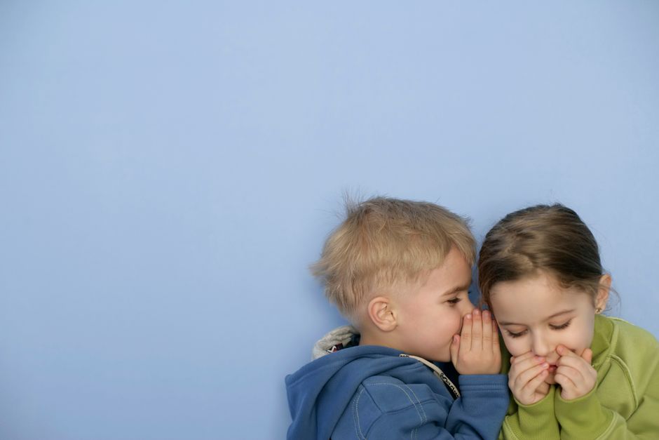 Twee kinderen fluisteren samen een geheim
