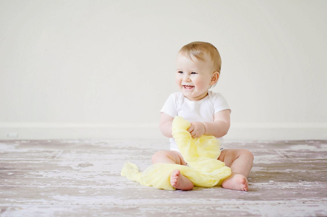 Een lachende baby op een gele deken